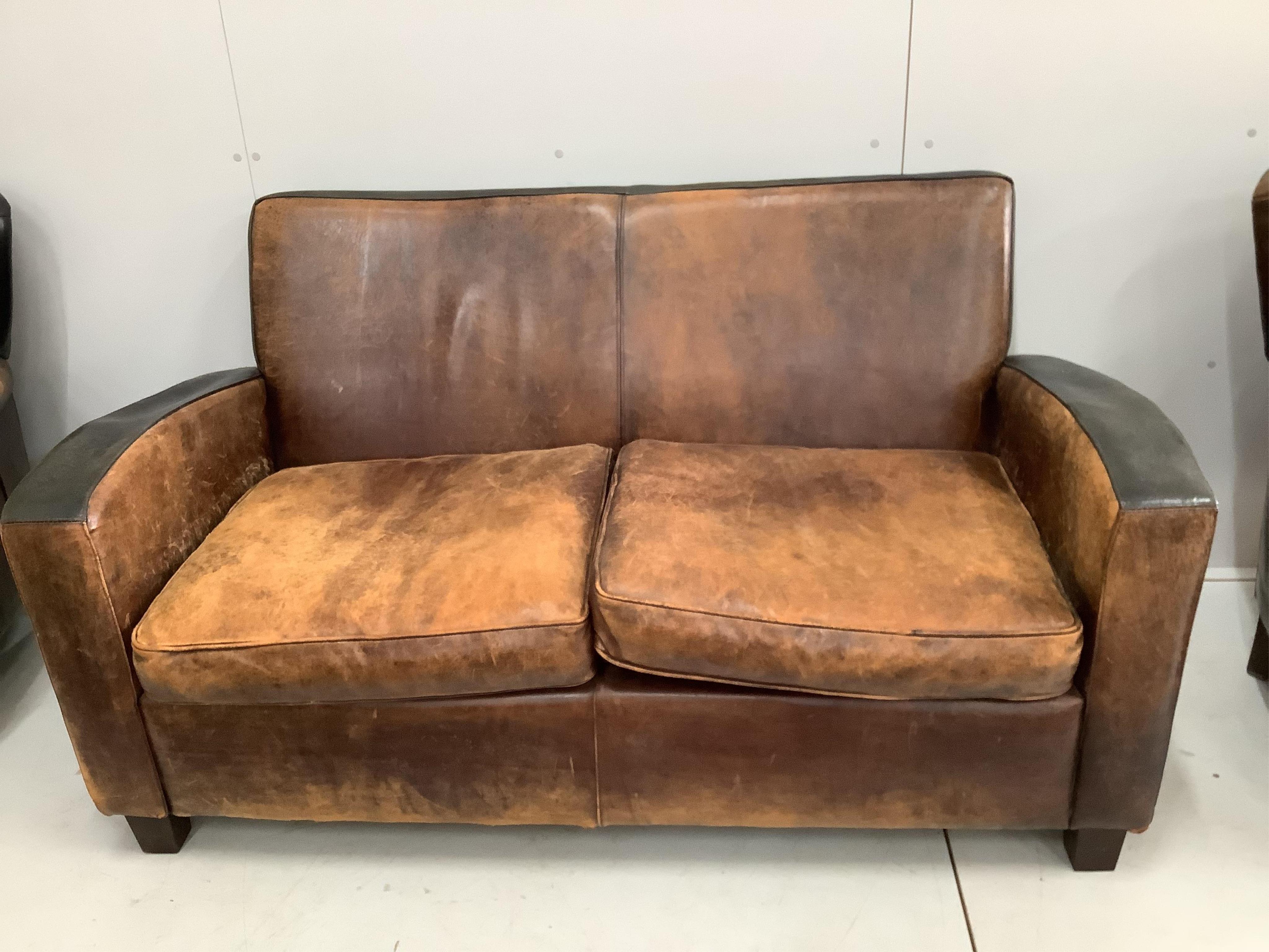 A leather settee, width 156cm, depth 78cm, height 82cm and a pair of leather wing armchairs. Condition - fair